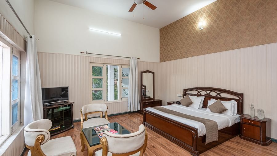 Spacious and bright guest room at DLS Tehri Club Resort with a king size bed and a seating area.